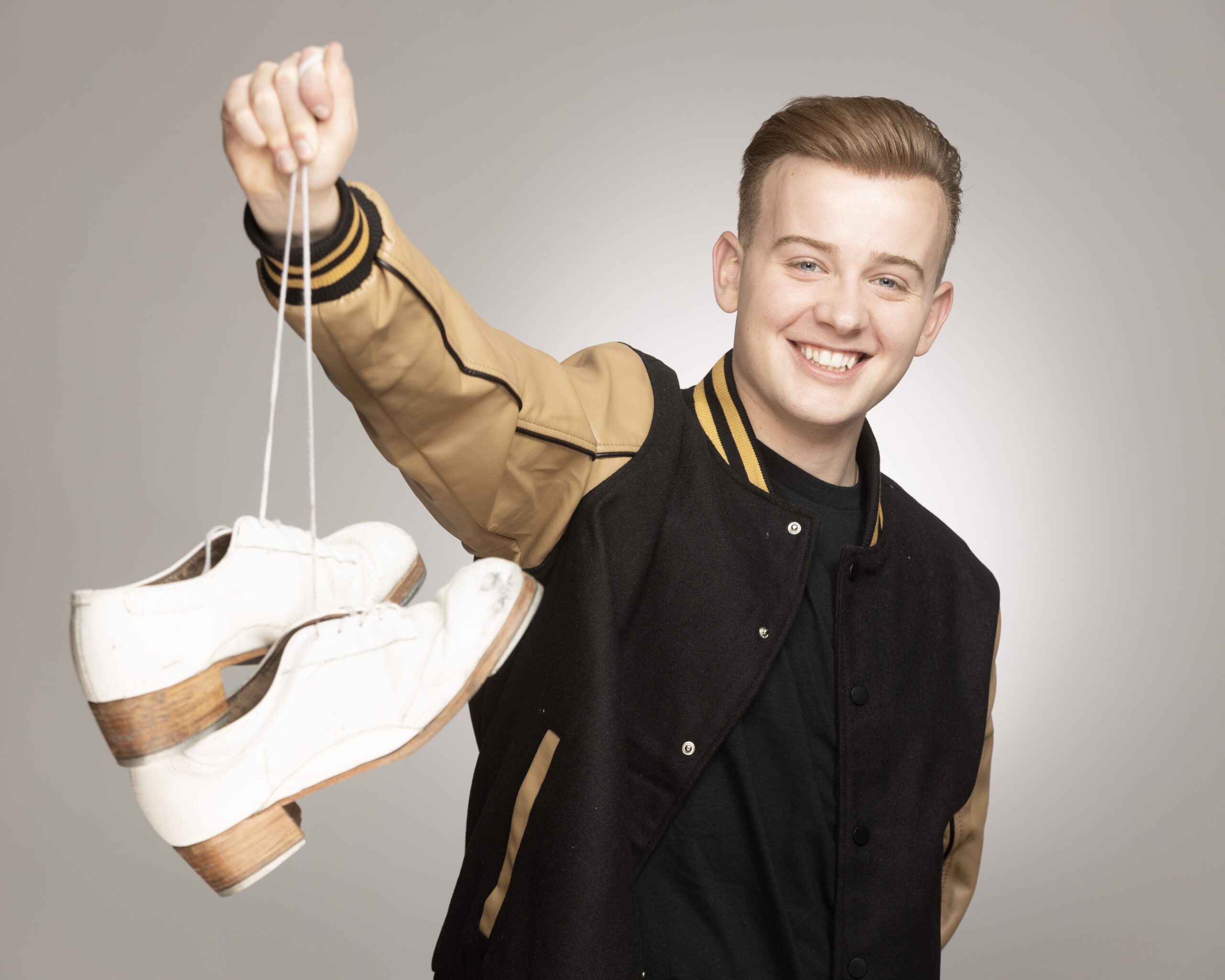 Ryan Maw holding a pair of tap shoes.
