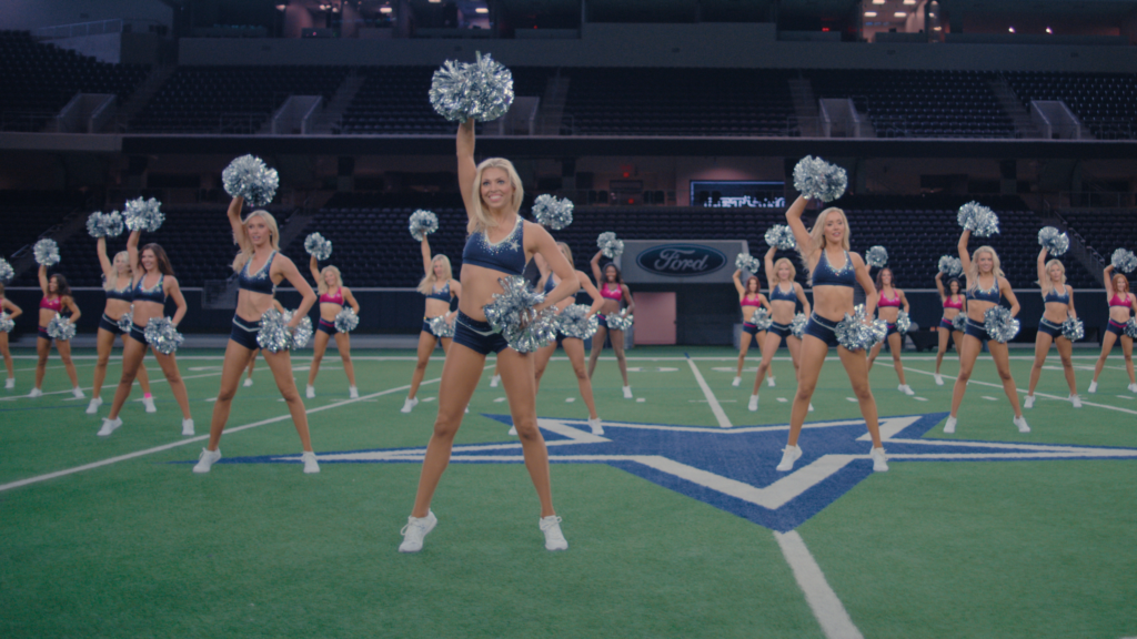 A group of cheerleaders in blue uniforms practice on the court 