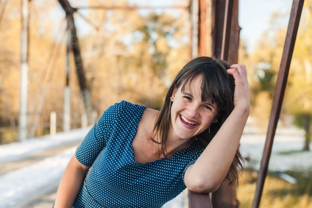 Adelle Welch smiling and leaning on a bridge's railing 