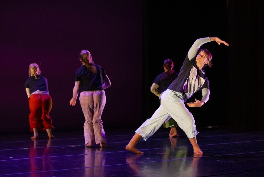 Adelle Welch dancing on stage with other female dancers wearing loose clothing 