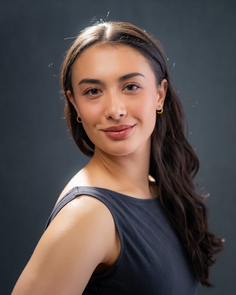 Ellie Daley's headshot against a dark background. Her hair is down and she's wearing a dark tank