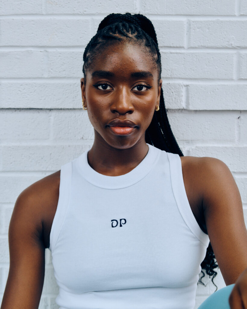 Caroline T Dartey's headshot against a white brick wall.