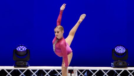 Margaret Jarvie dancing on stage wearing a long sleeved red leotard and performing an arabesque