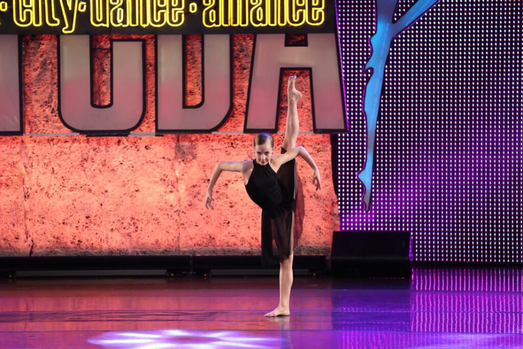 Rachel Quiner competing on stage waring a black flowy dress while performing a 180 tilt