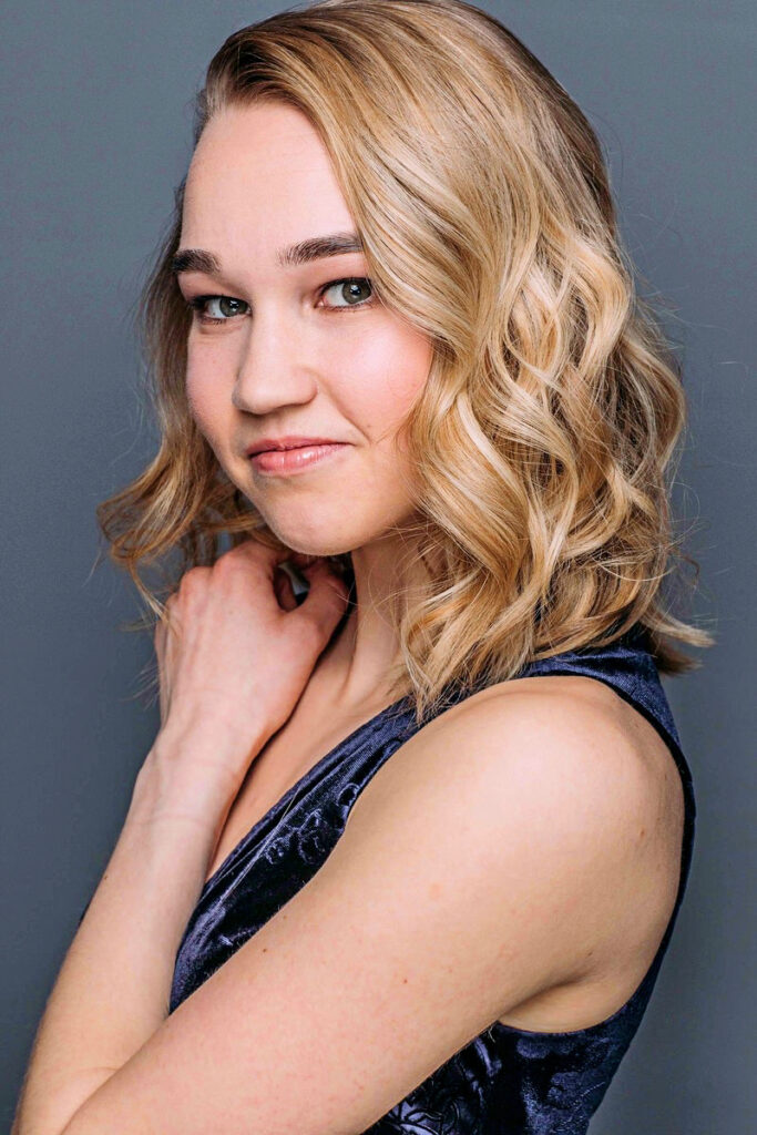 Kathleen Laituri's headshot. She has curly blonde hair and wears a blue tank top.