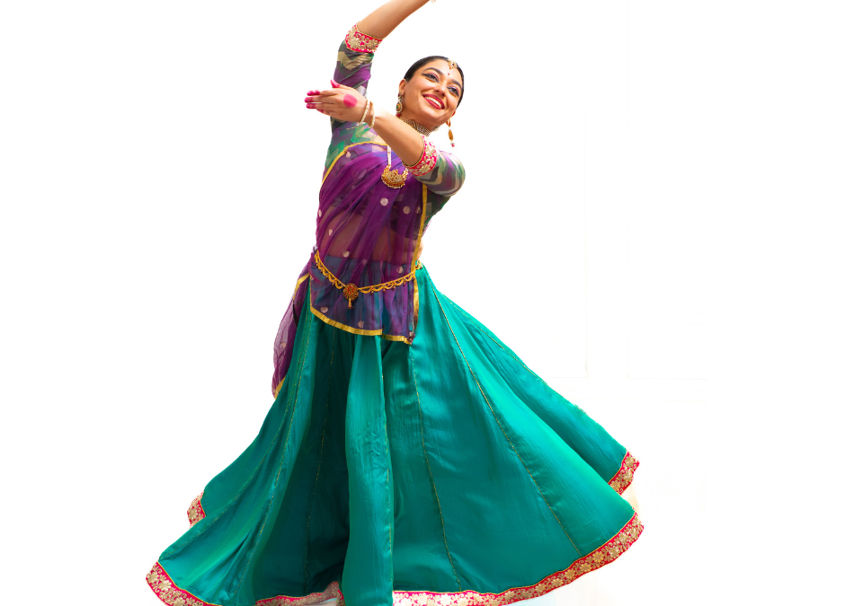 Radha Varadan lifting her arms while dancing in a colorful traditional dress.