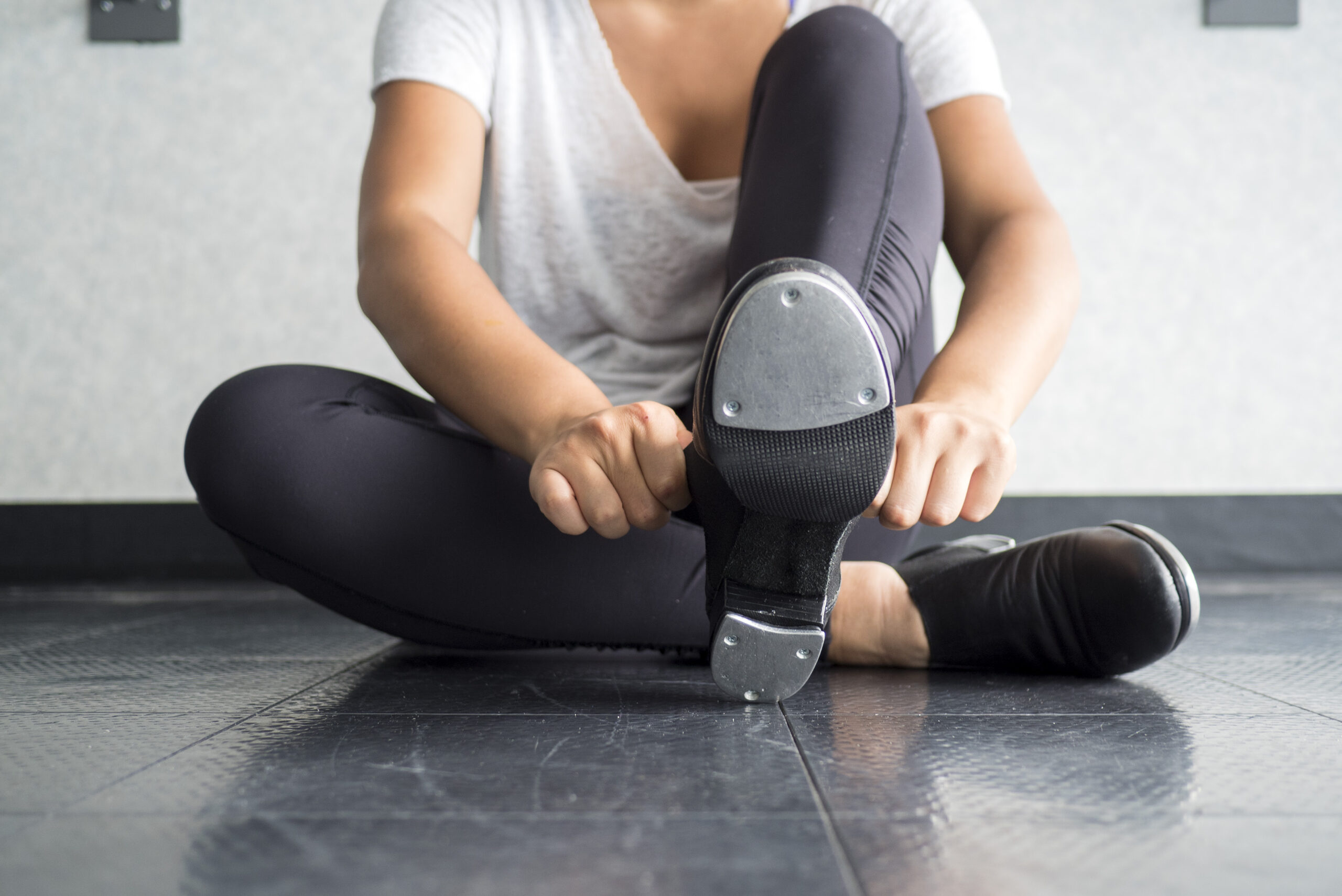 Tap dancer sliding on her tap shoes in the dance studio during dance class with a bottom view of the taps