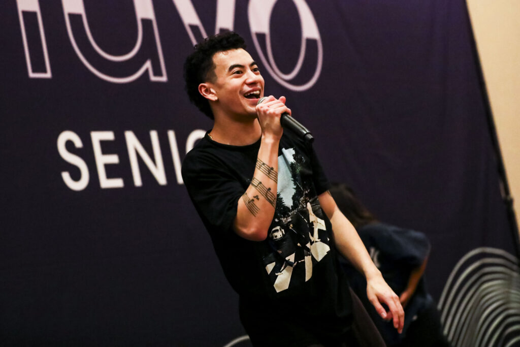 A male instructor speaking energetically into a microphone. 