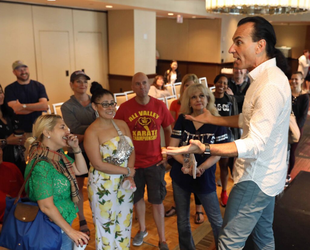 Joe Lanteri faces a group of dance parents and speaks to them animatedly during a presentation. 