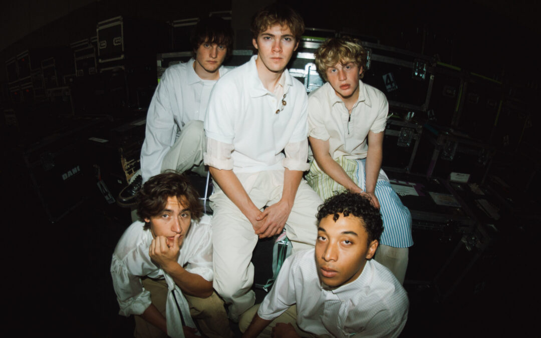 The five members of the Full Circle Boys pose for a group photo shot with a fish-eye lens. They all wear white shirts and khaki pants and look into the camera with relaxed expressions.