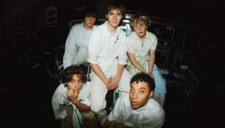 The five members of the Full Circle Boys pose for a group photo shot with a fish-eye lens. They all wear white shirts and khaki pants and look into the camera with relaxed expressions.