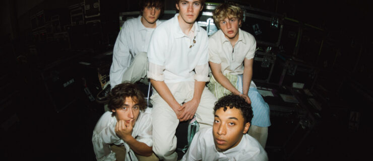 The five members of the Full Circle Boys pose for a group photo shot with a fish-eye lens. They all wear white shirts and khaki pants and look into the camera with relaxed expressions.