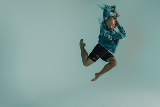Jakob Karr jumps with his torso twisted, arms bent and up, and legs bent at 90 degrees forward and backward.