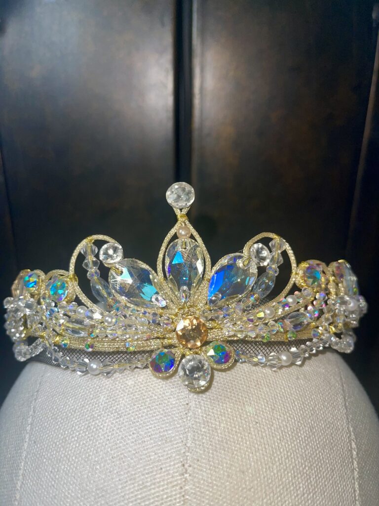 A ballet costume tiara with gold, white, and iridescent jewels.