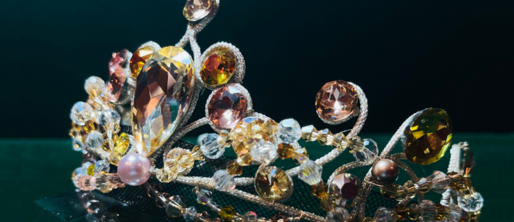 A close-up of a ballet costume tiara with white, amber, and light pink gems.