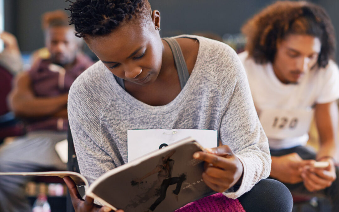 Shot of a young female dancer reading a dance magazine in a classroom.