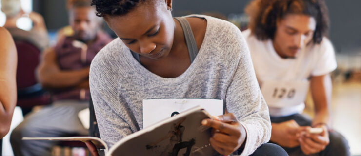 Shot of a young female dancer reading a dance magazine in a classroom.