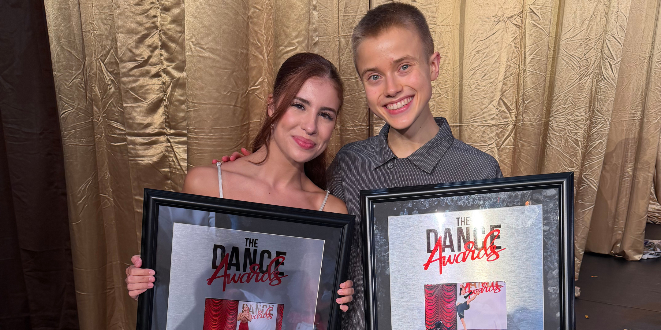 Cameron Voorhees and Ian Stegeman pose together in formal attire holding their respective dance awards. Behind them is a shimmery gold curtain.