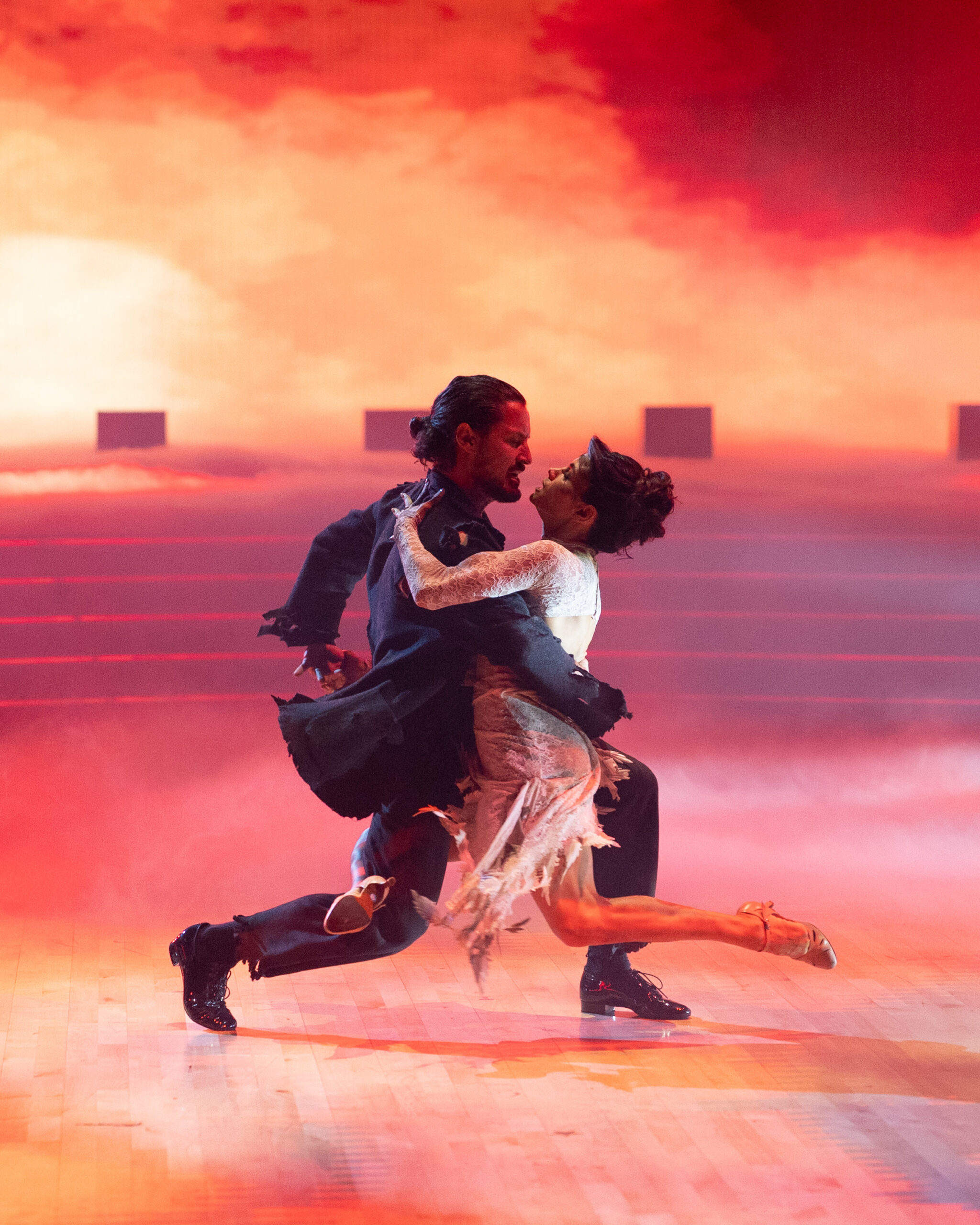Val Chmerkovskiy lunges forward as Jenna Dewan makes the same position in the air, wrapping her front leg around Chmerkovskiy's back leg. They hold each other close and stare into each other's eyes.