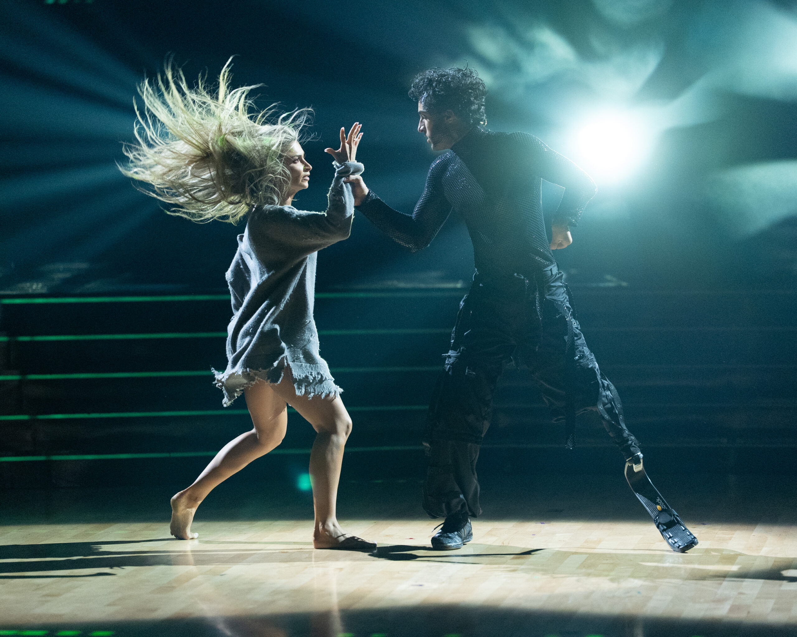 Daniella Karagach and Ezra Frech turn toward each other, Frech clasping Karagach's wrist as her long hair flies behind her.