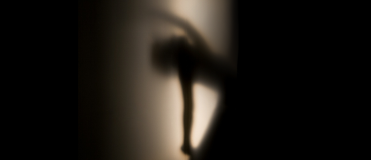 A hazy silhouette of a dancer in profile, lit from behind with a soft, spooky glow.