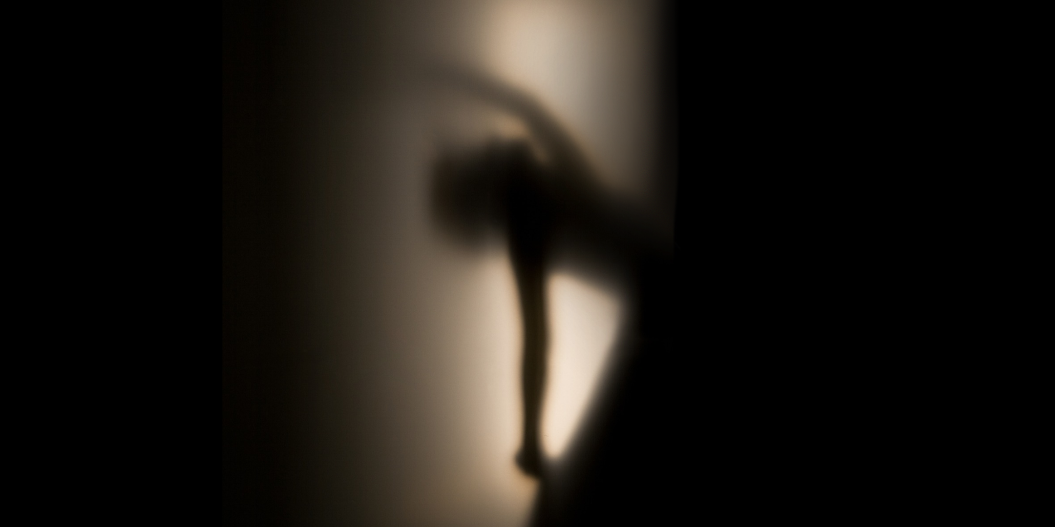 A hazy silhouette of a dancer in profile, lit from behind with a soft, spooky glow.